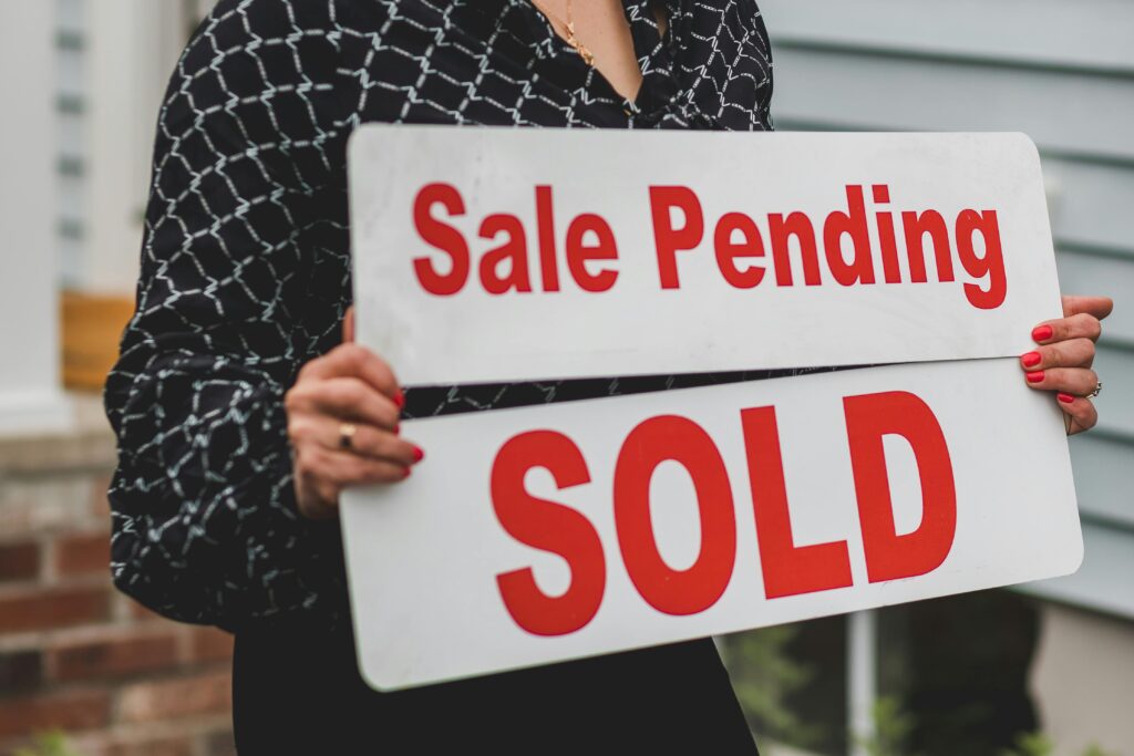 pexels photo 8292794 8292794 A businesswoman holding 'Sale Pending' and 'Sold' signs indicating a successful real estate transaction.